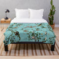Soft and plush aqua-colored blanket with playful monkey and jungle plant designs