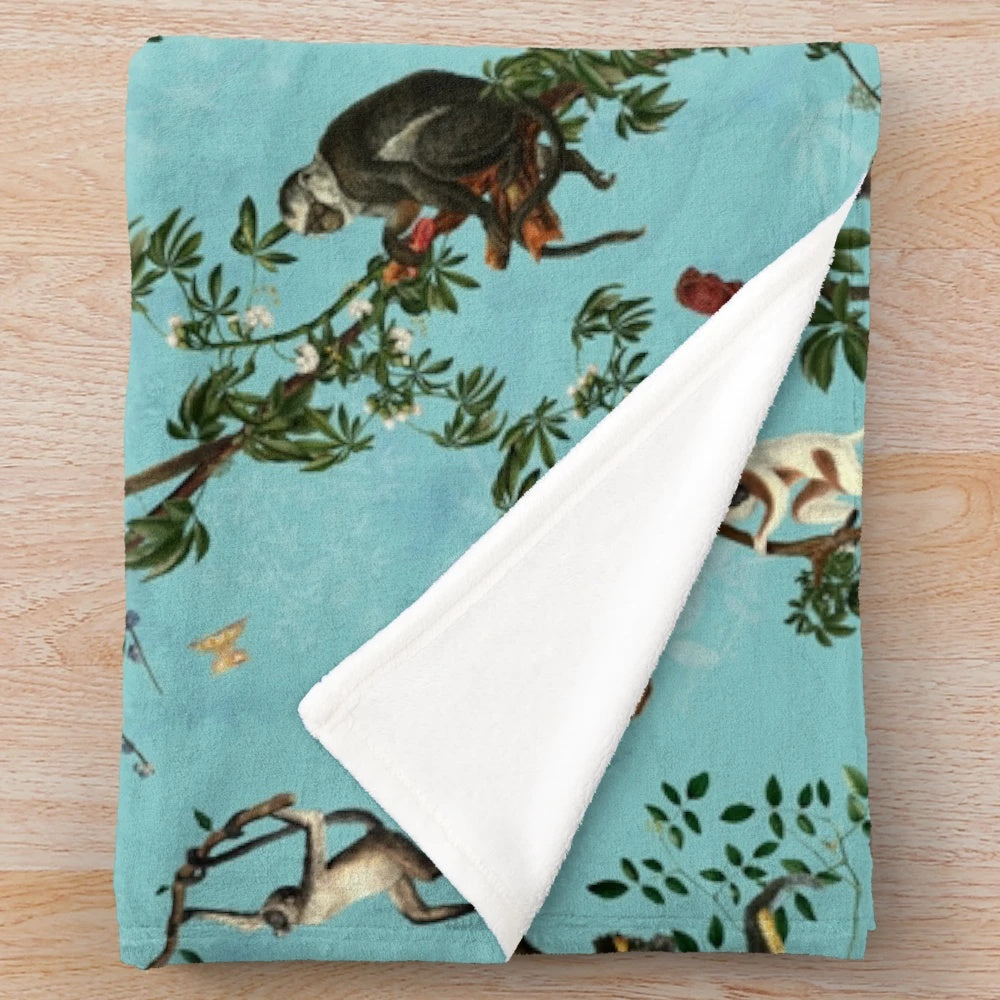 Soft and plush aqua-colored blanket with playful monkey and jungle plant designs