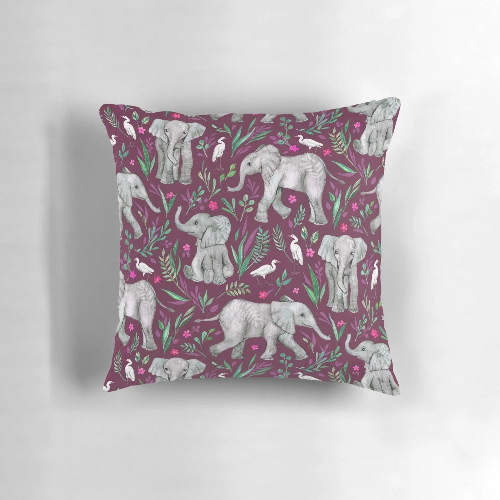 Whimsical watercolor painting of baby elephants and egret birds on a burgundy red throw pillow