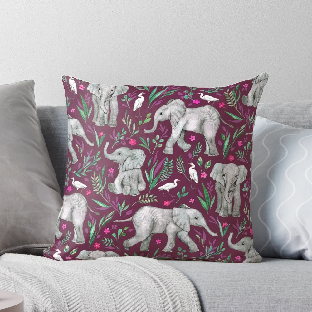 Whimsical watercolor painting of baby elephants and egret birds on a burgundy red throw pillow