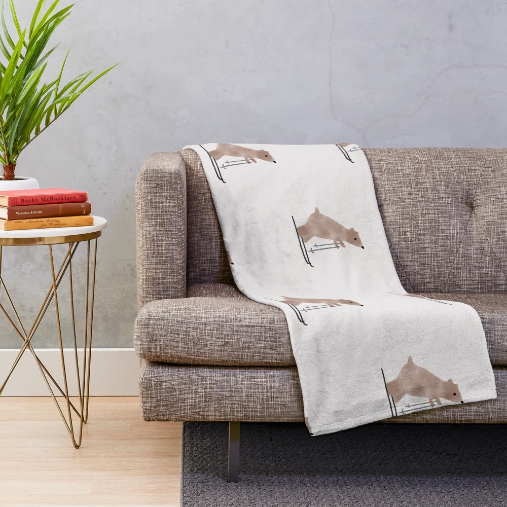 A whimsical plush blanket featuring a watercolor-style illustration of a bear on skis in a snowy, winter landscape
