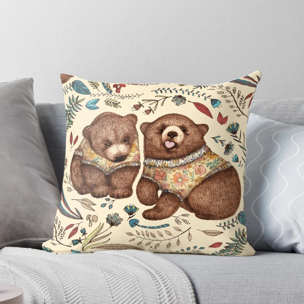 A decorative throw pillow featuring a whimsical illustration of two brown bear cubs surrounded by fantastical forest flora.