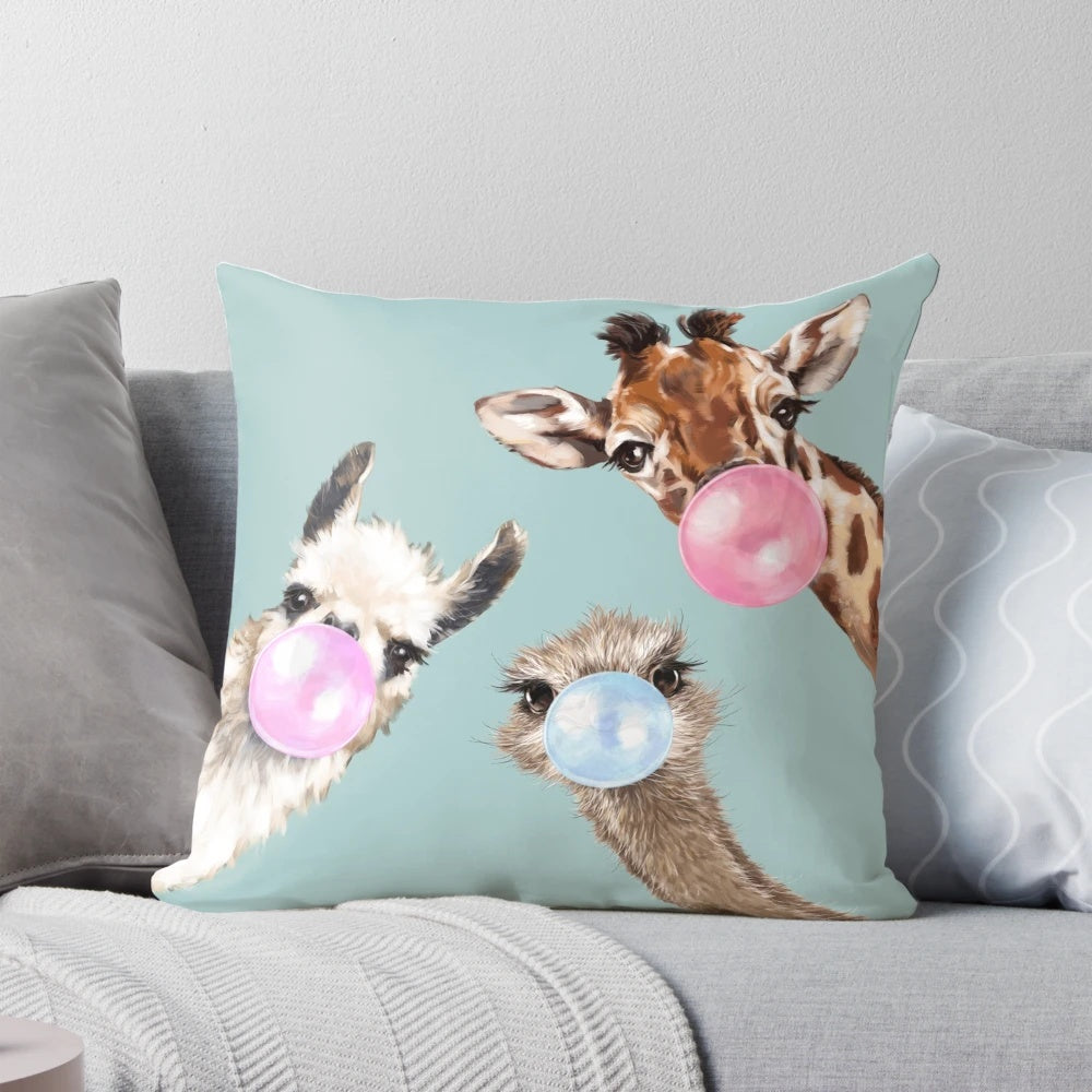 Colorful illustration of a bubble gum-chewing llama, ostrich, and giraffe on a blue pillow
