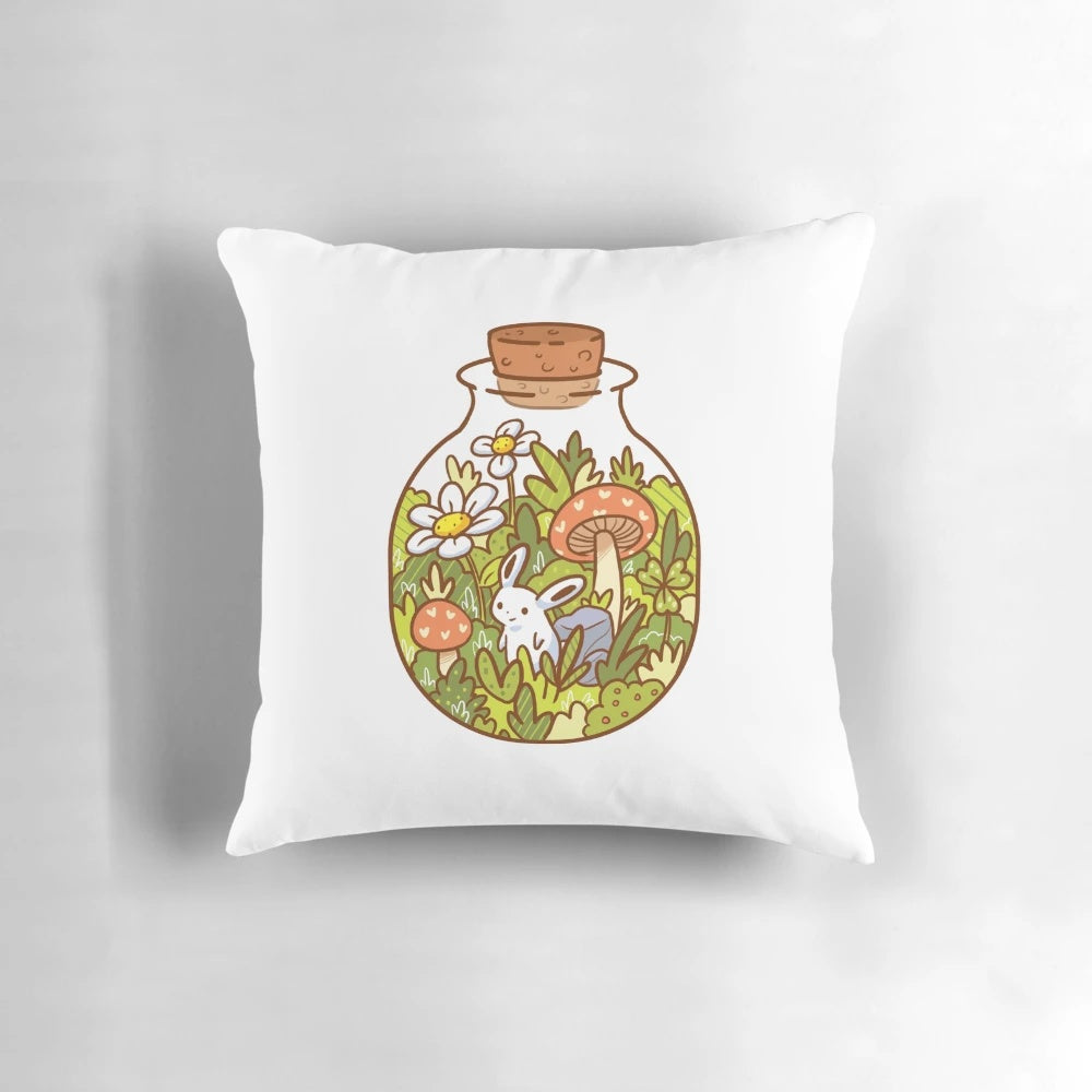 A soft, plush pillow featuring a delightful bunny in a glass bottle, surrounded by lush foliage and nature-inspired elements.