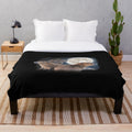 Adorable capybara characters sitting on a crescent moon against a starry night sky on a soft, cozy plush blanket