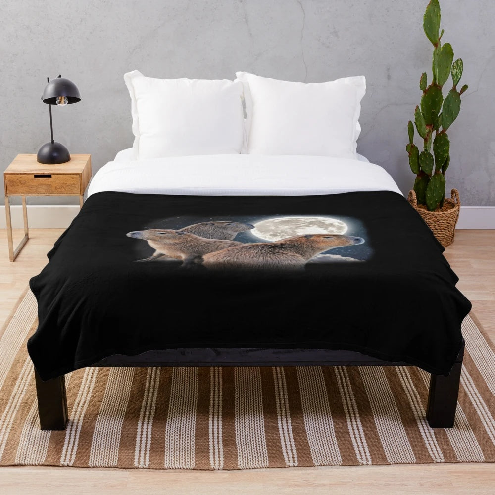 Adorable capybara characters sitting on a crescent moon against a starry night sky on a soft, cozy plush blanket