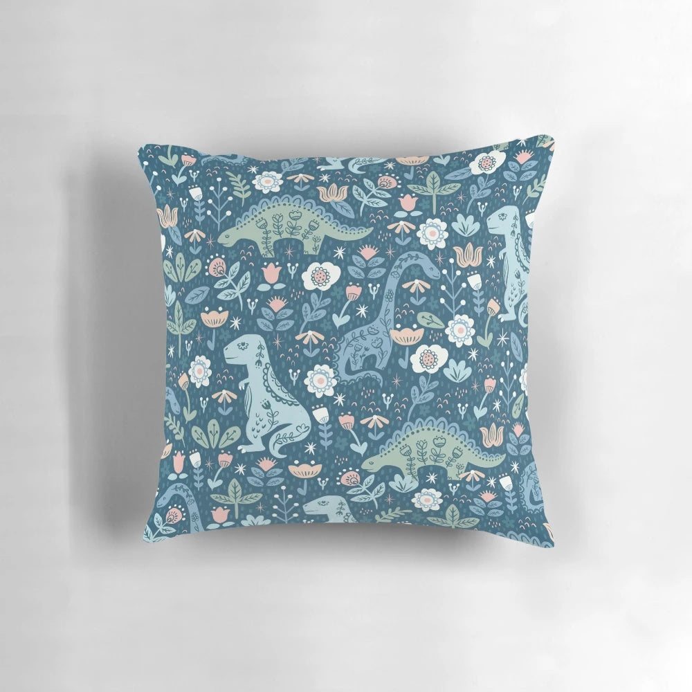 A decorative throw pillow featuring a colorful, folk-inspired dinosaur design in shades of blue.