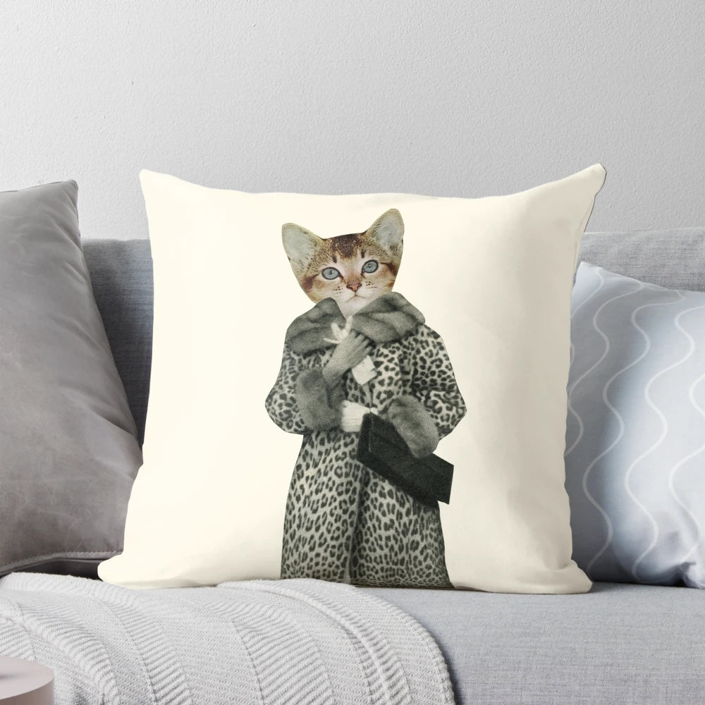 A white and orange kitten wearing a leopard print dress and posing on a pillow