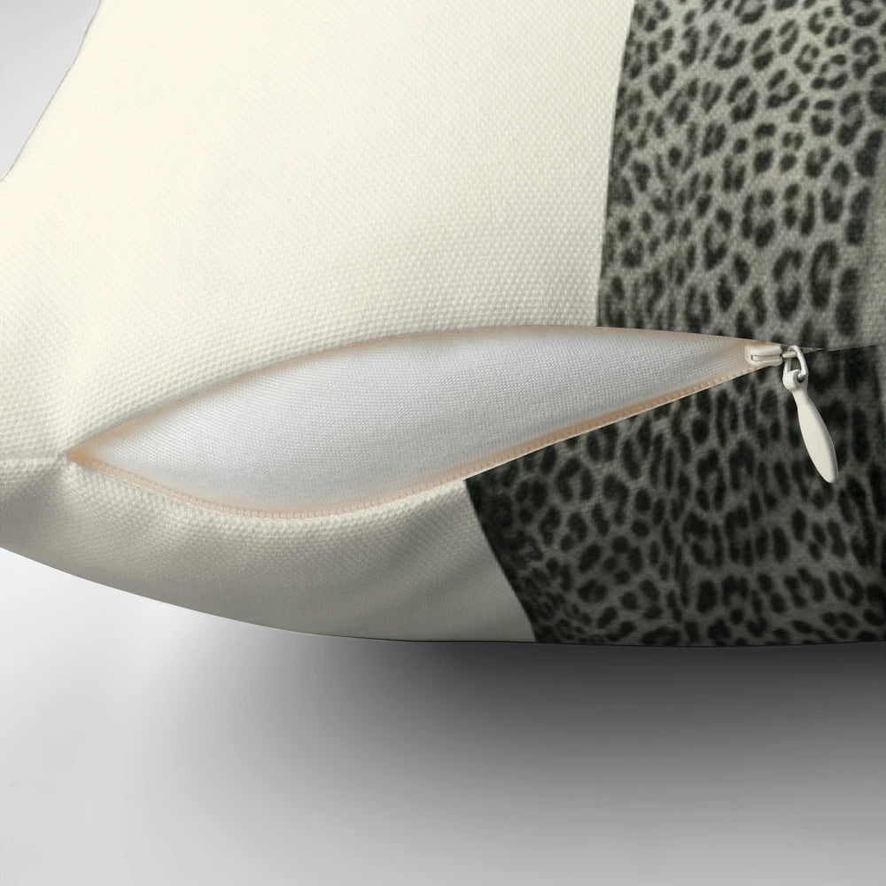 A white and orange kitten wearing a leopard print dress and posing on a pillow
