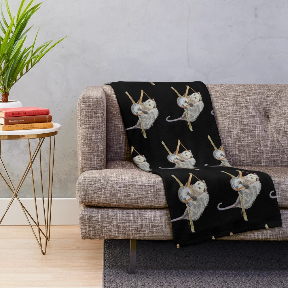 Soft, cozy plush blanket featuring a watercolor illustration of a trash-loving opossum playing the banjo.