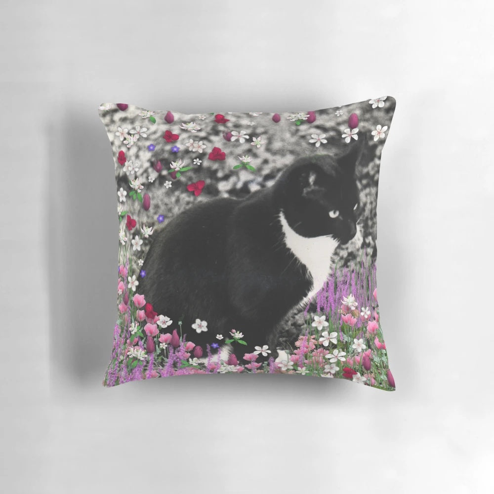 A whimsical pillow featuring a tuxedo cat surrounded by a colorful floral meadow