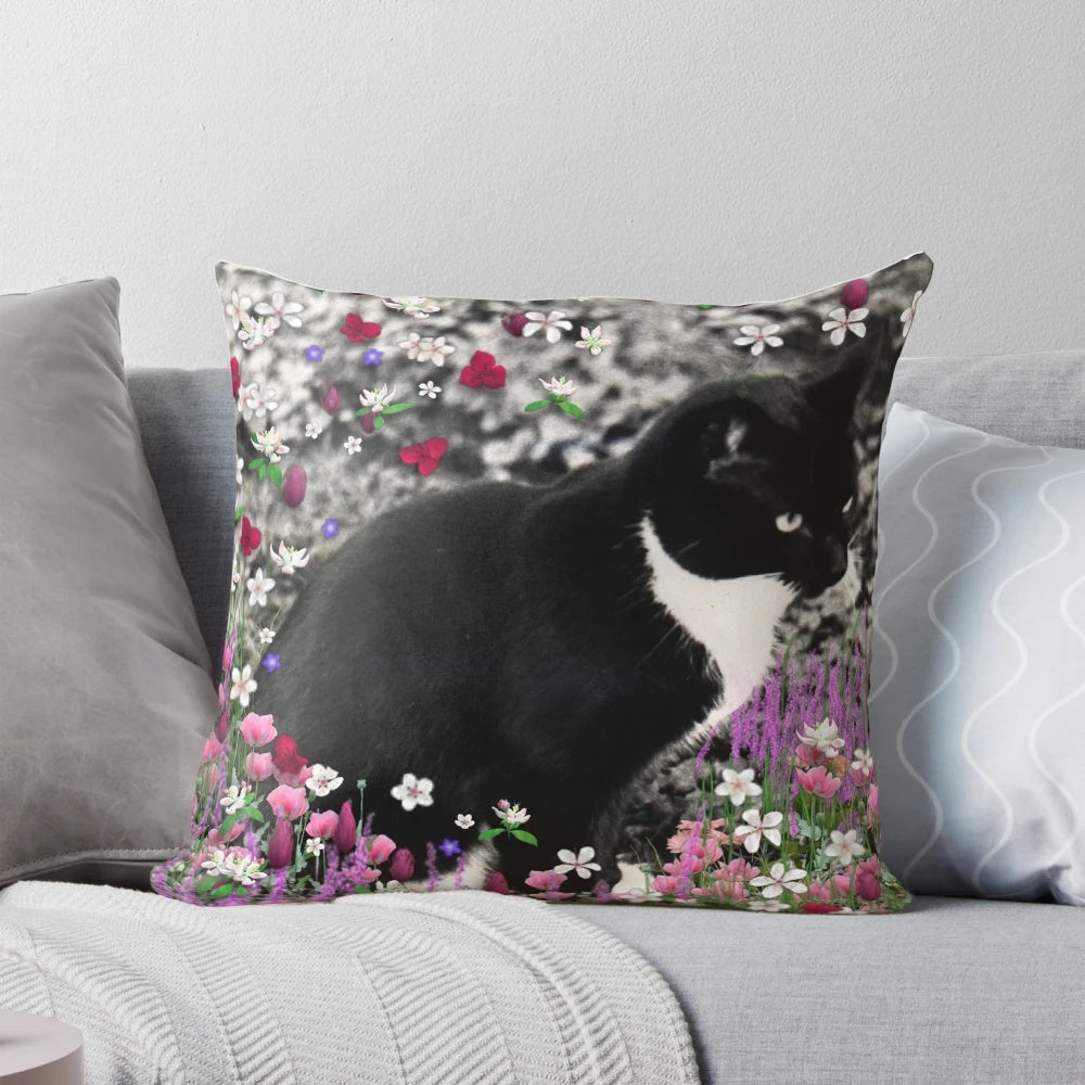 A whimsical pillow featuring a tuxedo cat surrounded by a colorful floral meadow