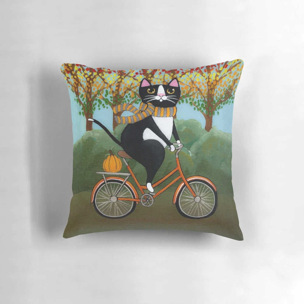 A tuxedo cat riding a bicycle surrounded by autumn leaves and pumpkins