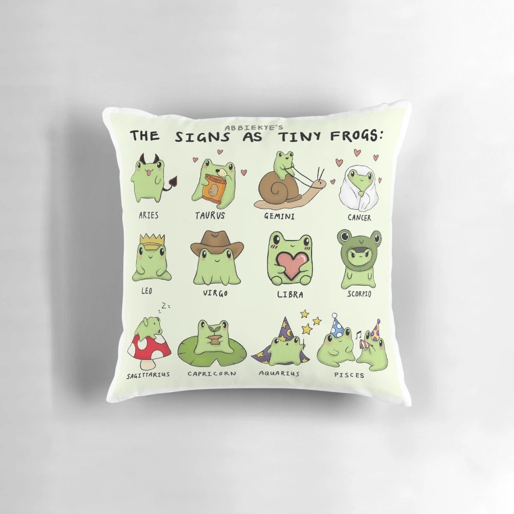 Decorative pillow featuring tiny frog illustrations representing the different zodiac signs